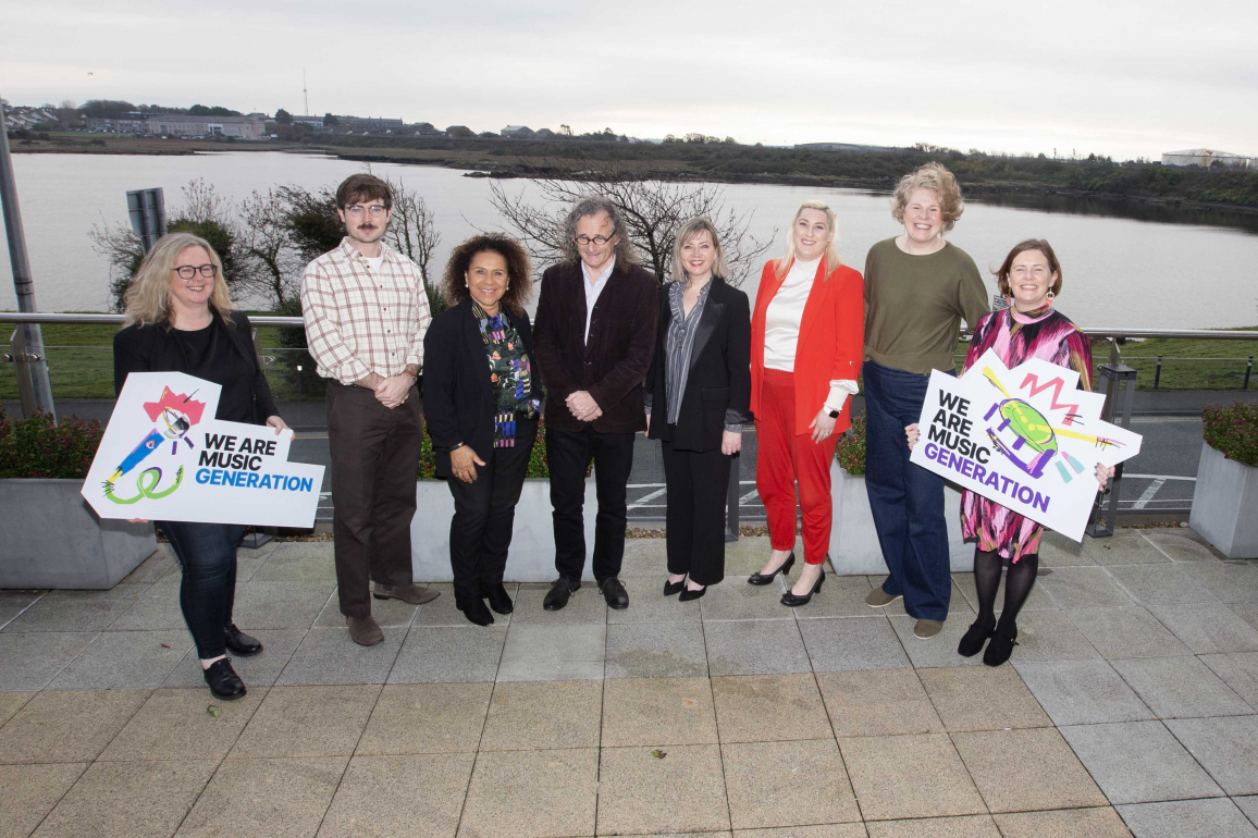 8 artists and musicians pose and hold We are Music Generation Signs